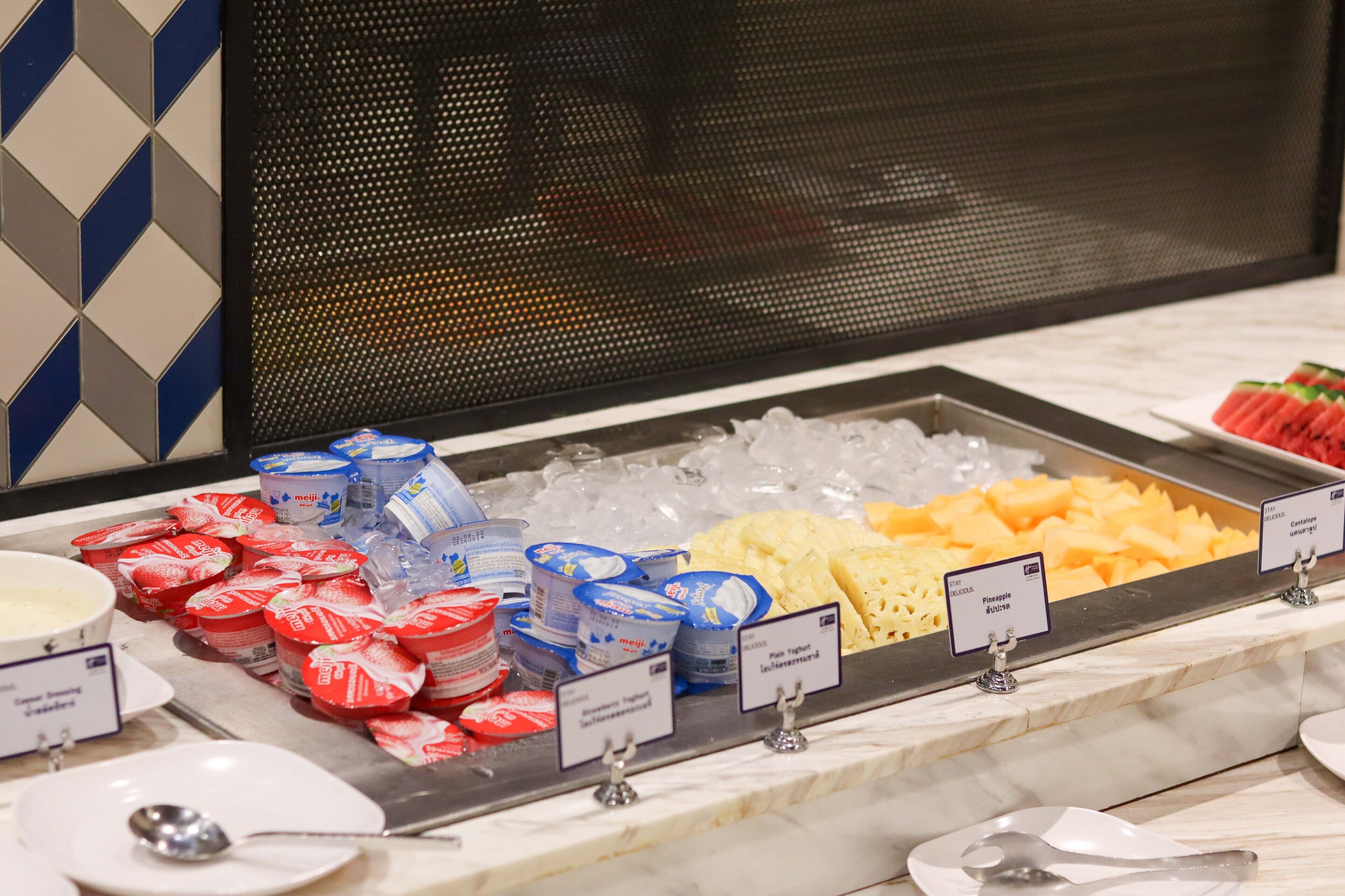A buffet with various food items and containers, including yogurt, cheese, and ice.