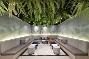 A modern lounge area with a sofa, ottomans, and a coffee table. - Holiday Inn Express Bangkok Sukhumvit 11 by IHG (Bangkok)