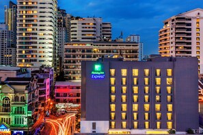 A hotel with a prominent 'Holiday Inn Express' sign, surrounded by high-rise buildings and a busy street with light trails. - Holiday Inn Express Bangkok Sukhumvit 11 by IHG (Bangkok)