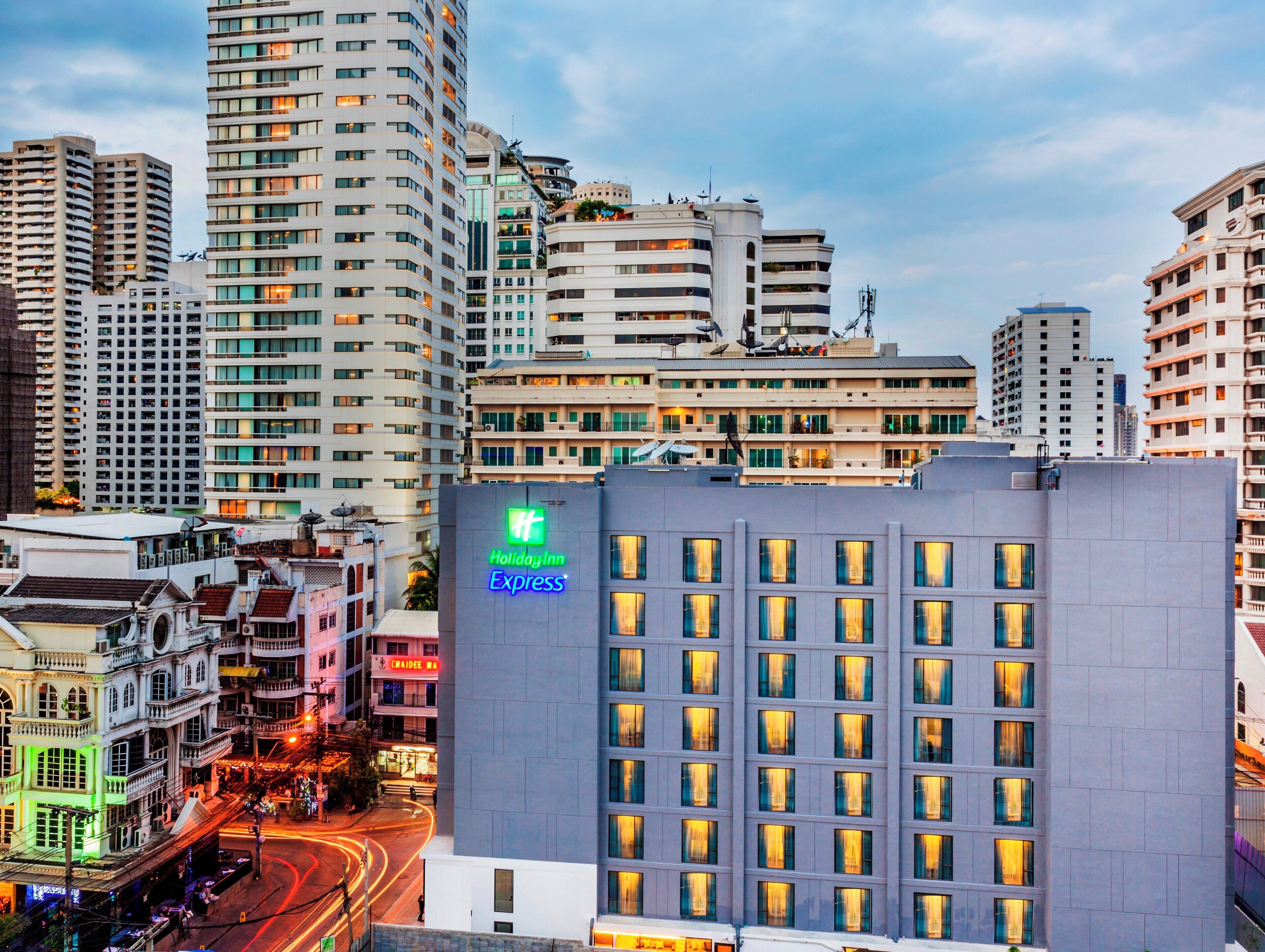 Edifício Holiday Inn Express com design moderno, situado em um centro urbano cercado por arranha-céus.