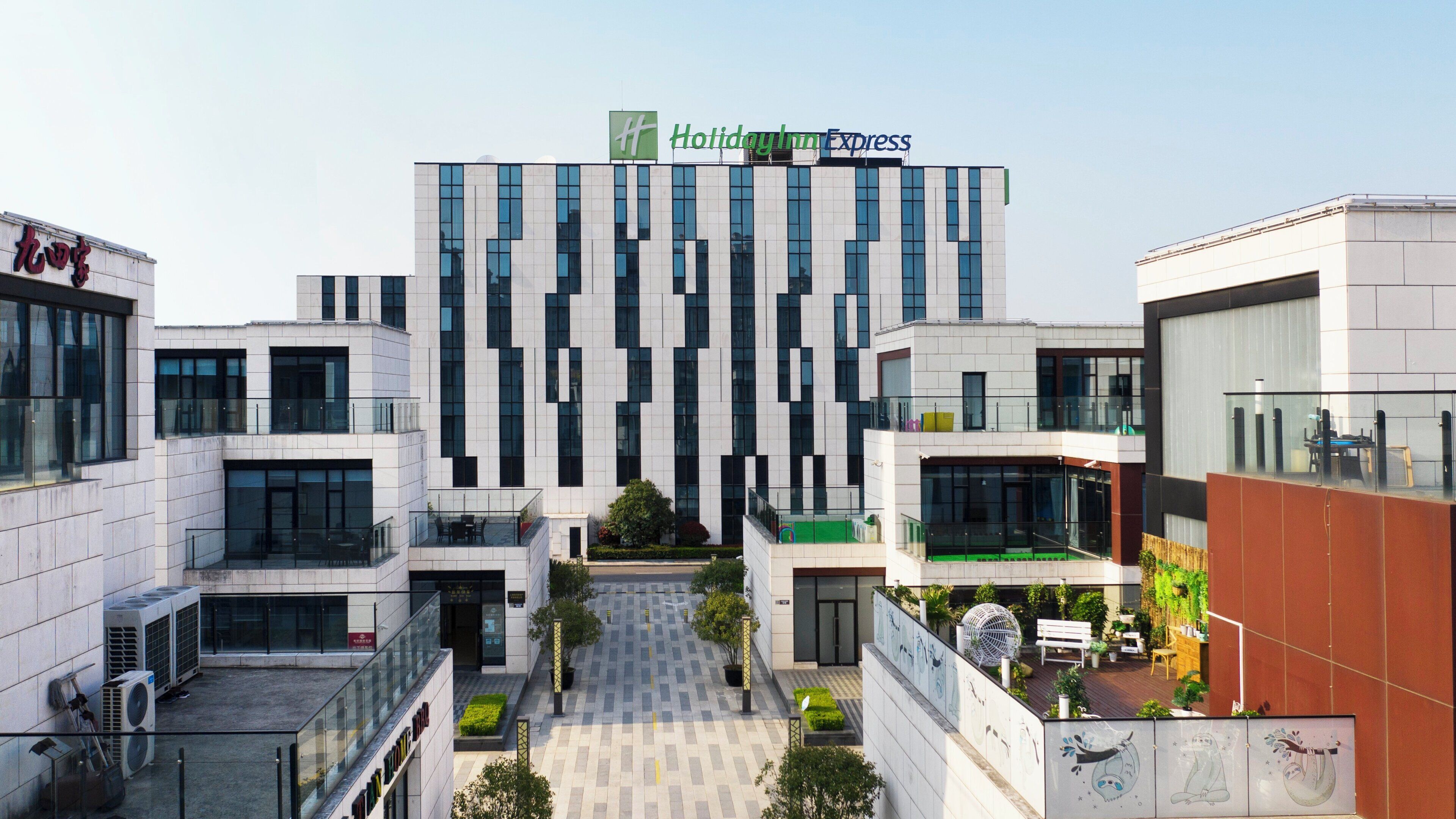 A Holiday Inn Express hotel with a modern architectural design, featuring a central courtyard with seating and greenery.