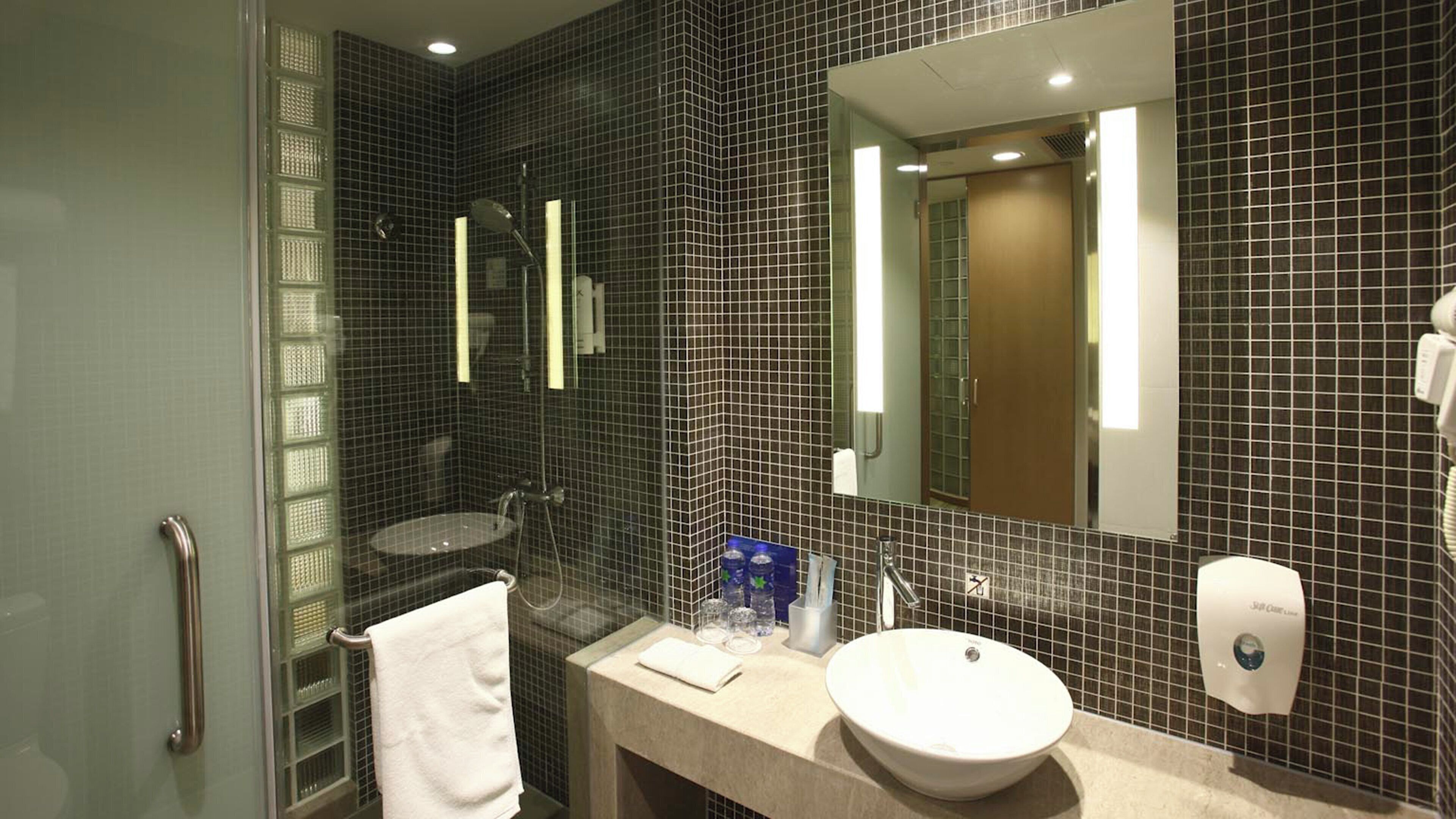 A bathroom with a sink, mirror, and shower.