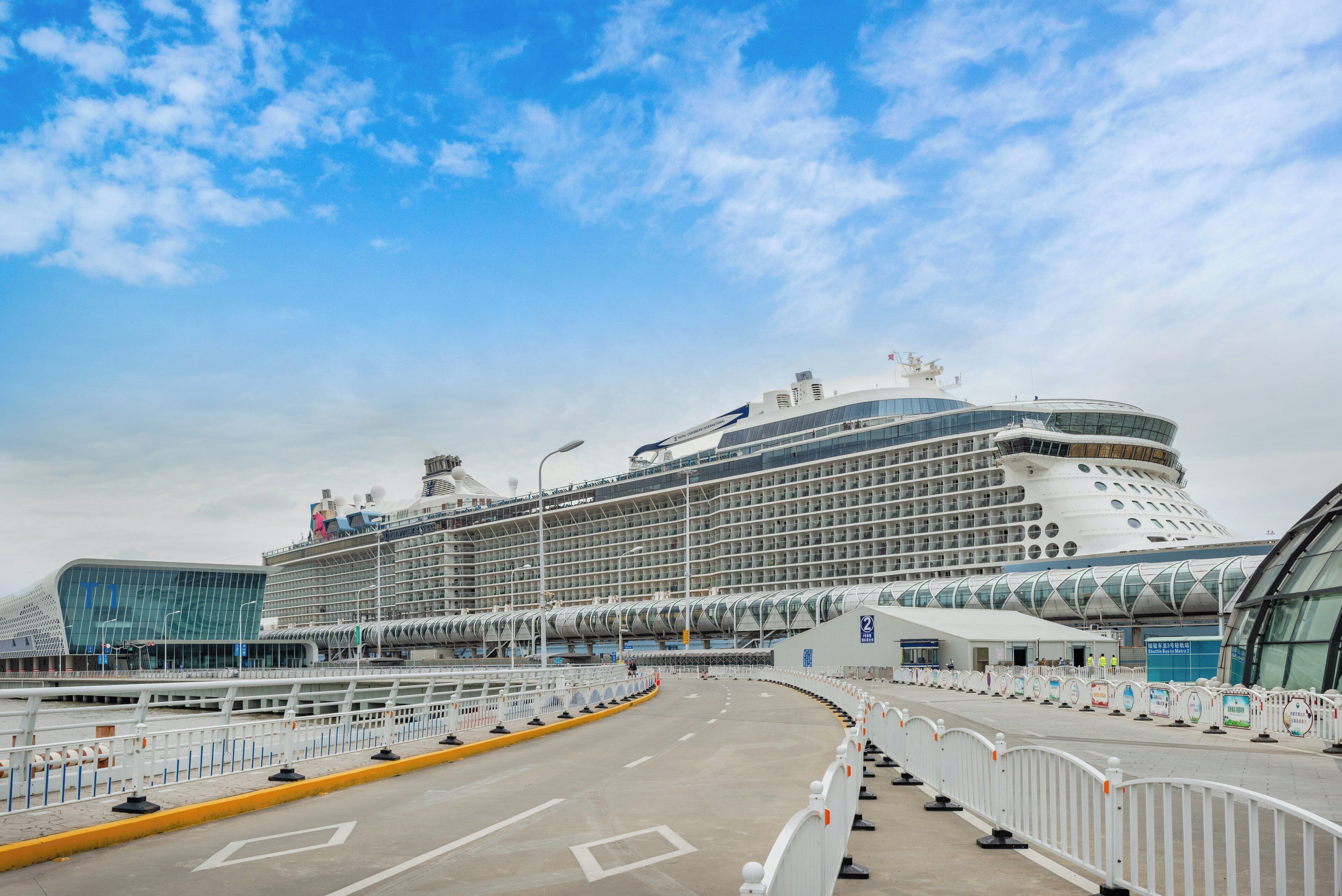 Un crucero amarrado en un puerto con un moderno edificio terminal al frente.