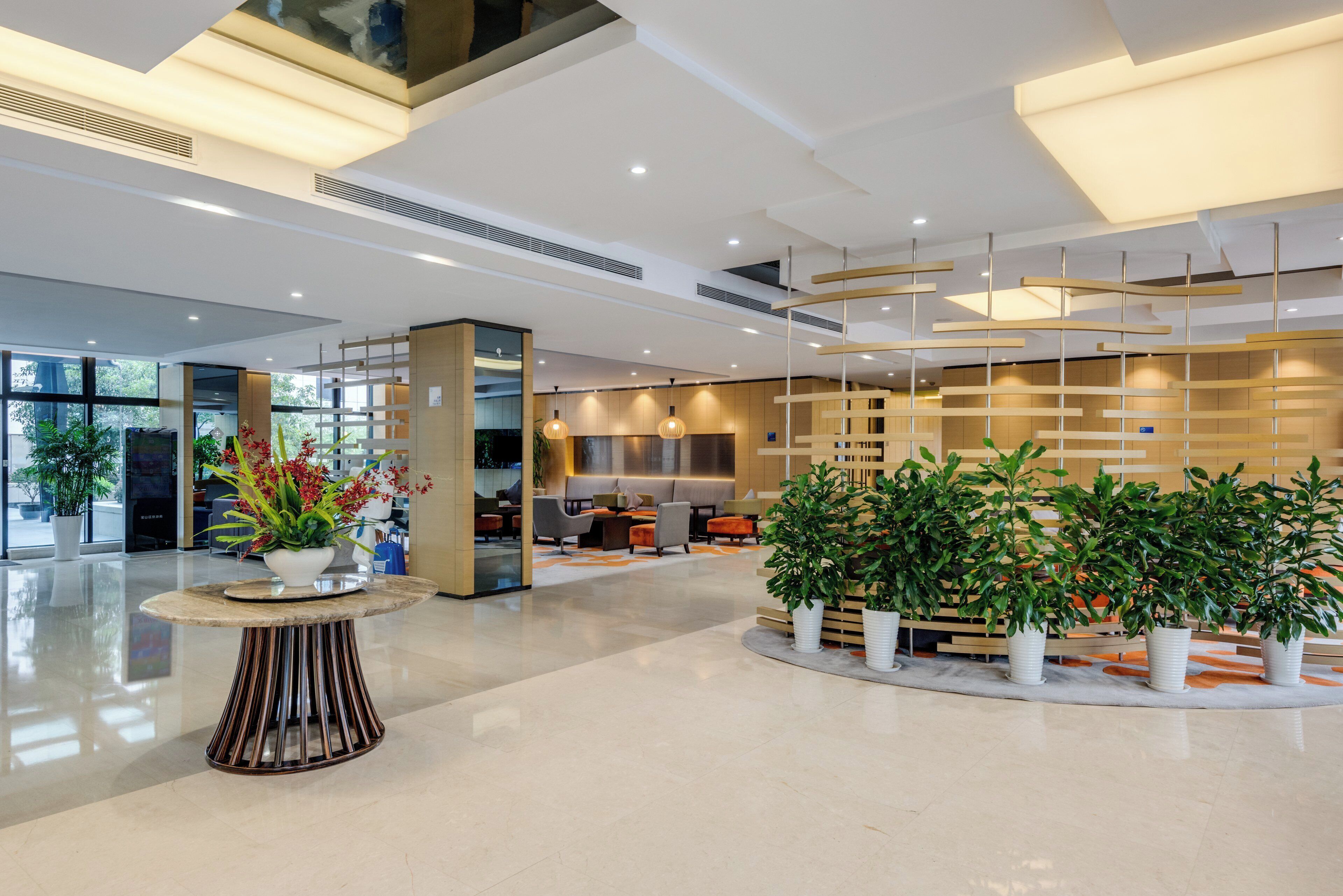 A modern lobby with a central seating area, a reception desk, and a plant arrangement.