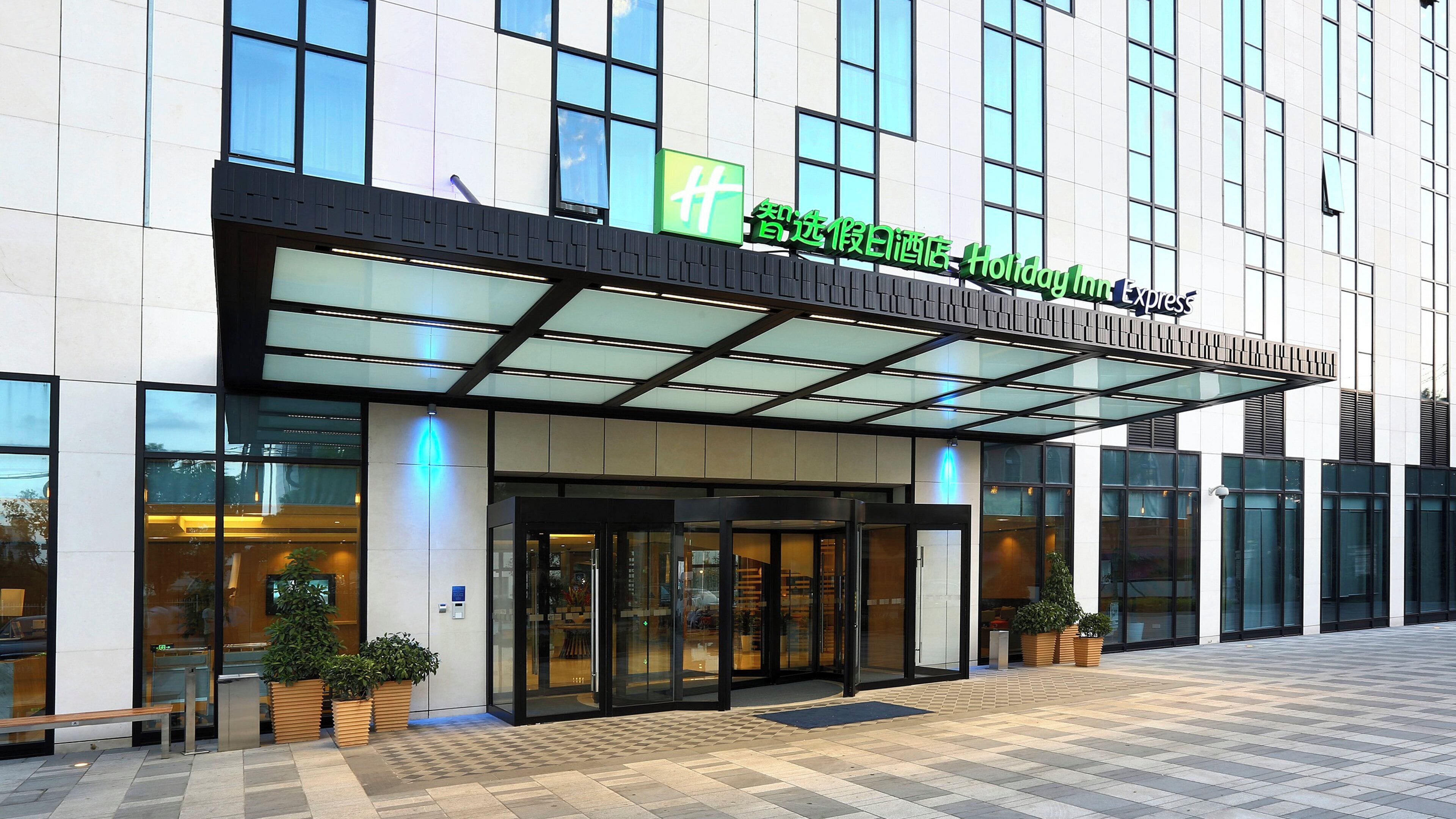 A Holiday Inn Express hotel with a modern facade, large windows, and a covered entrance.