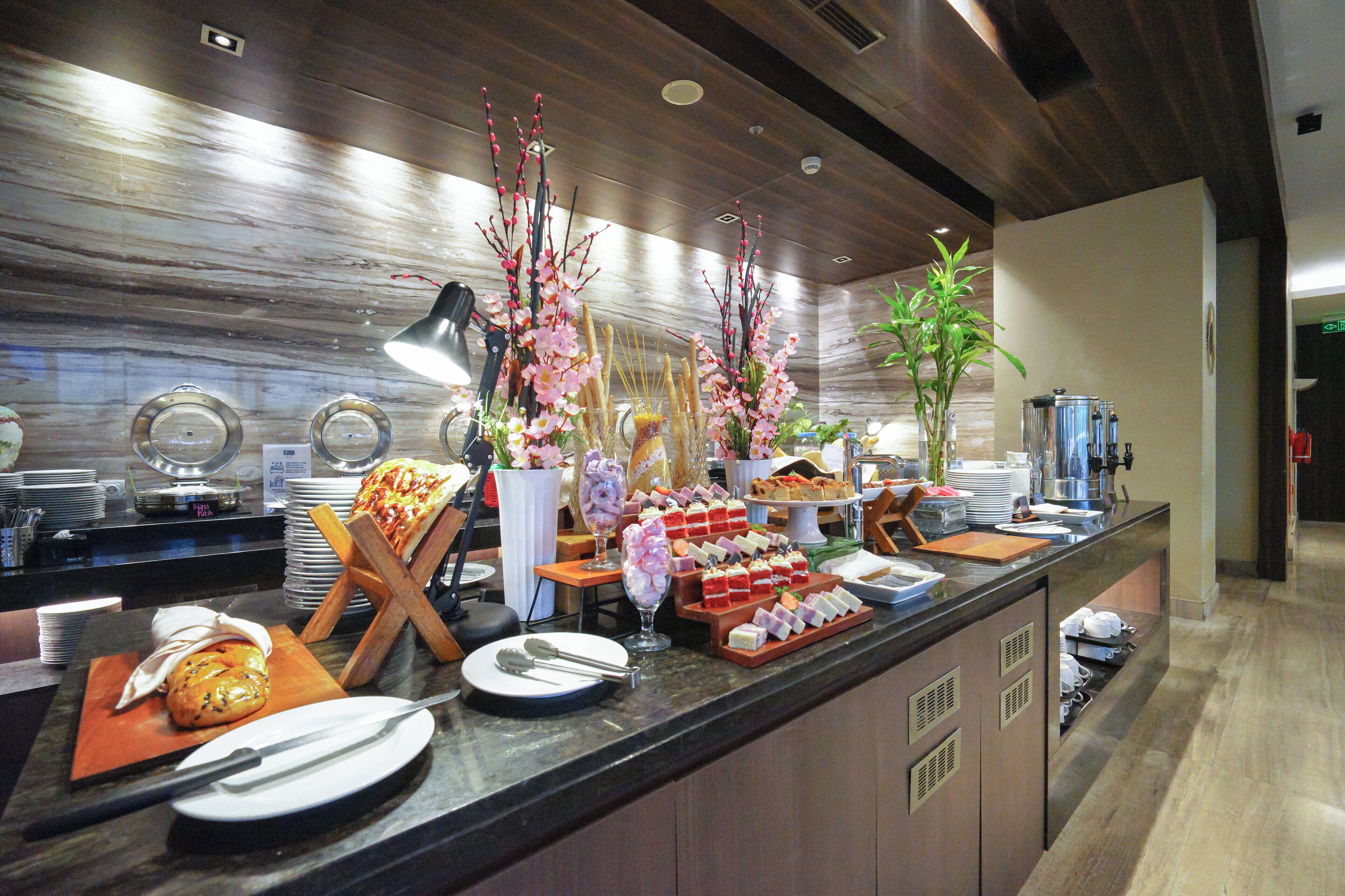 A buffet setup with various food items, a coffee machine, and decorative plants.