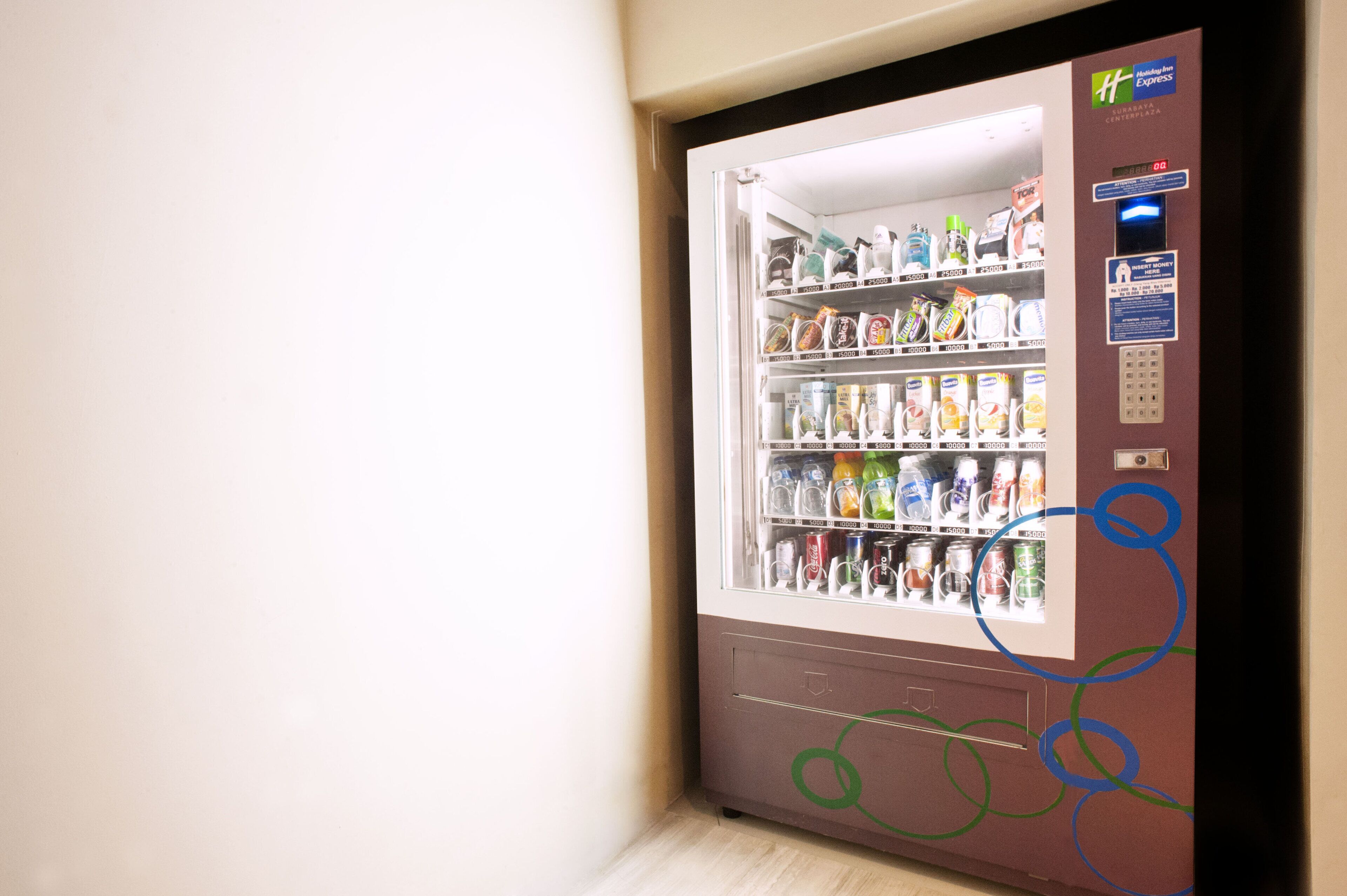 A vending machine with various snacks and drinks, a payment slot, and a Holiday Inn Express logo.