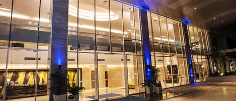 Un hotel moderno con fachada de vidrio, amplias ventanas y un interior bien iluminado.