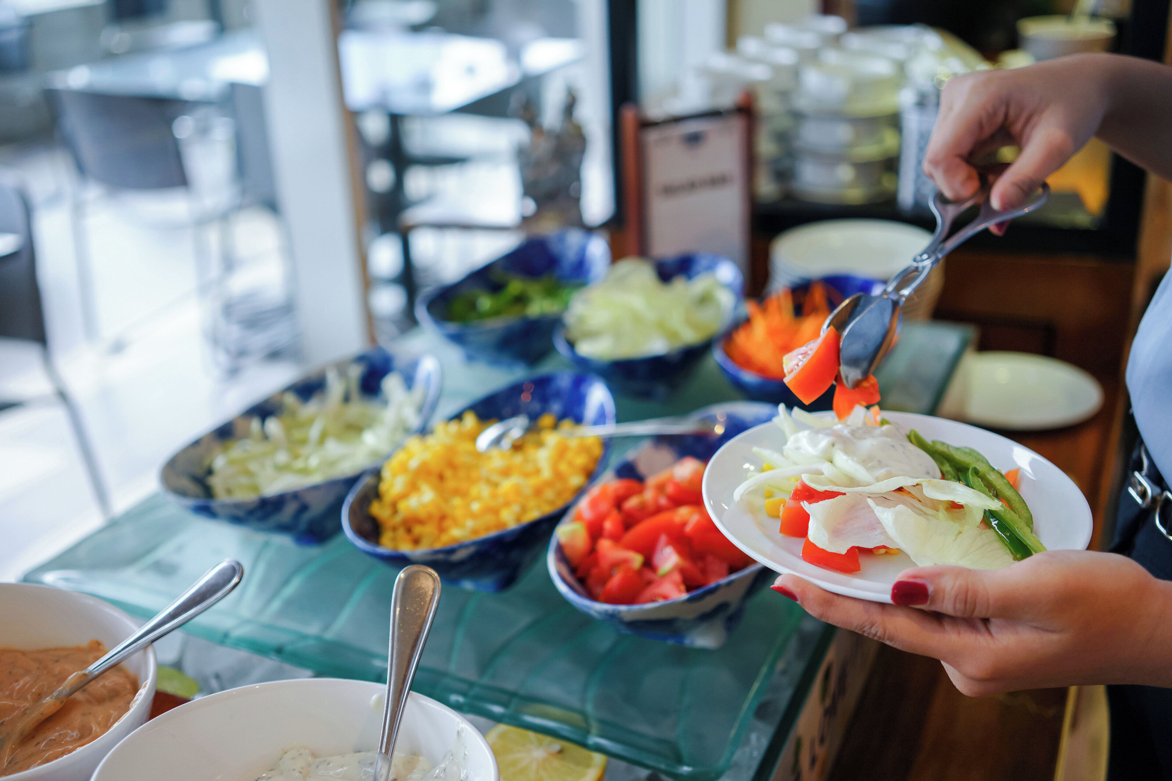 A buffet table with various food items and a person serving themselves.