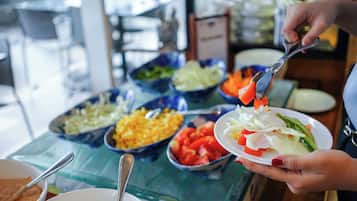A buffet table with various food items and a person serving themselves.