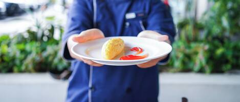 A person in a blue uniform holding a plate with a food item and sauce.