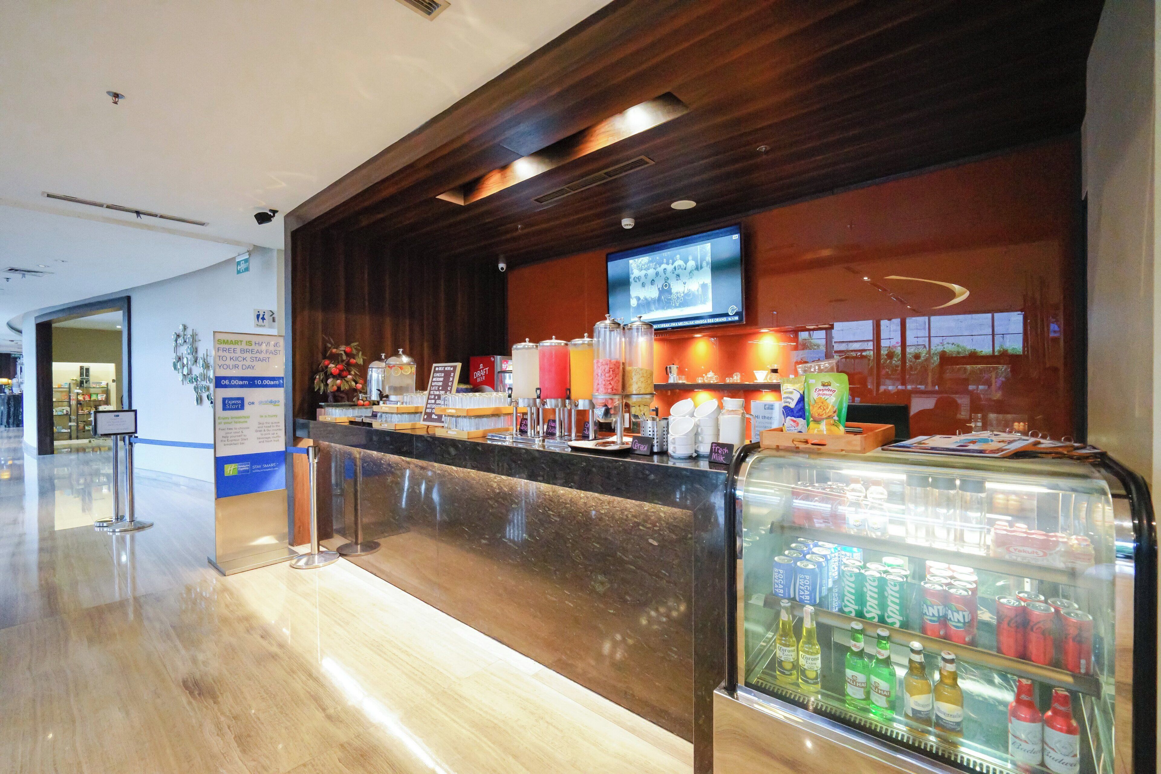 A hotel reception area with a marble counter, a beverage dispenser, and a television mounted on the wall.