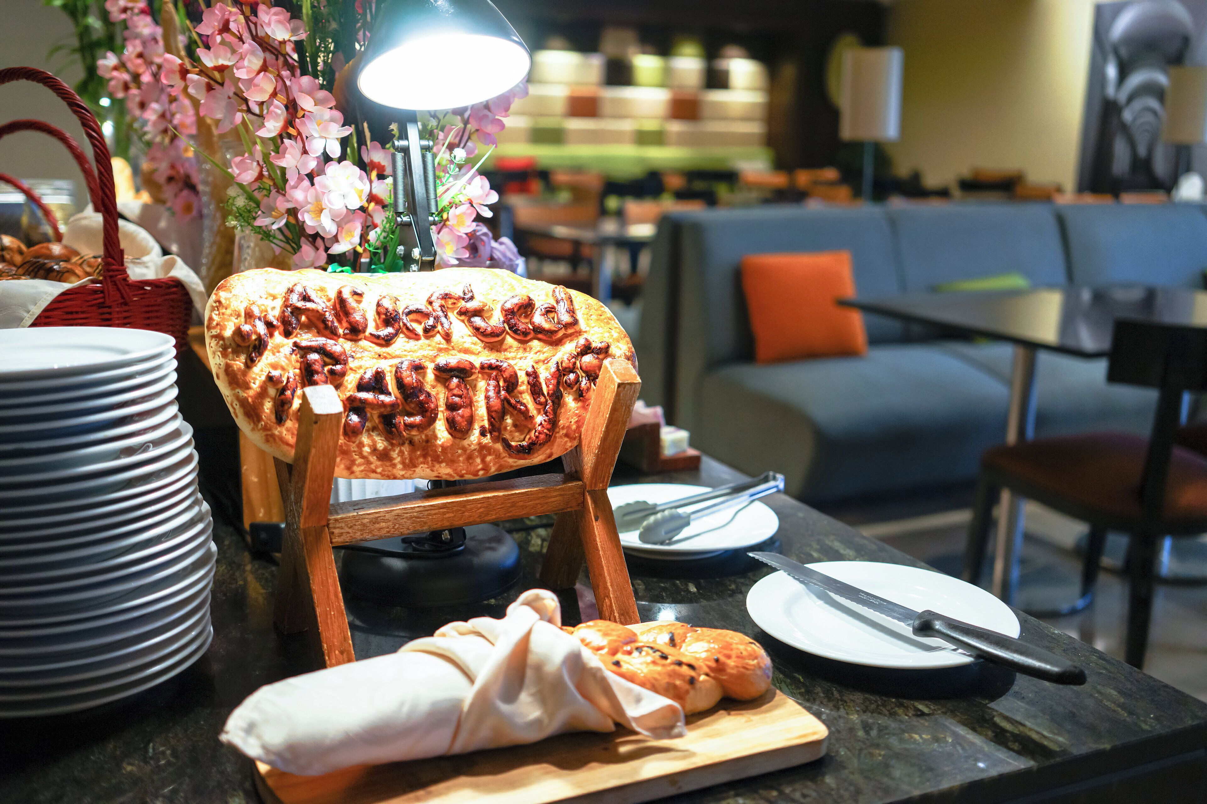 A buffet setup with a variety of food items, including a bread display, plates, and cutlery.