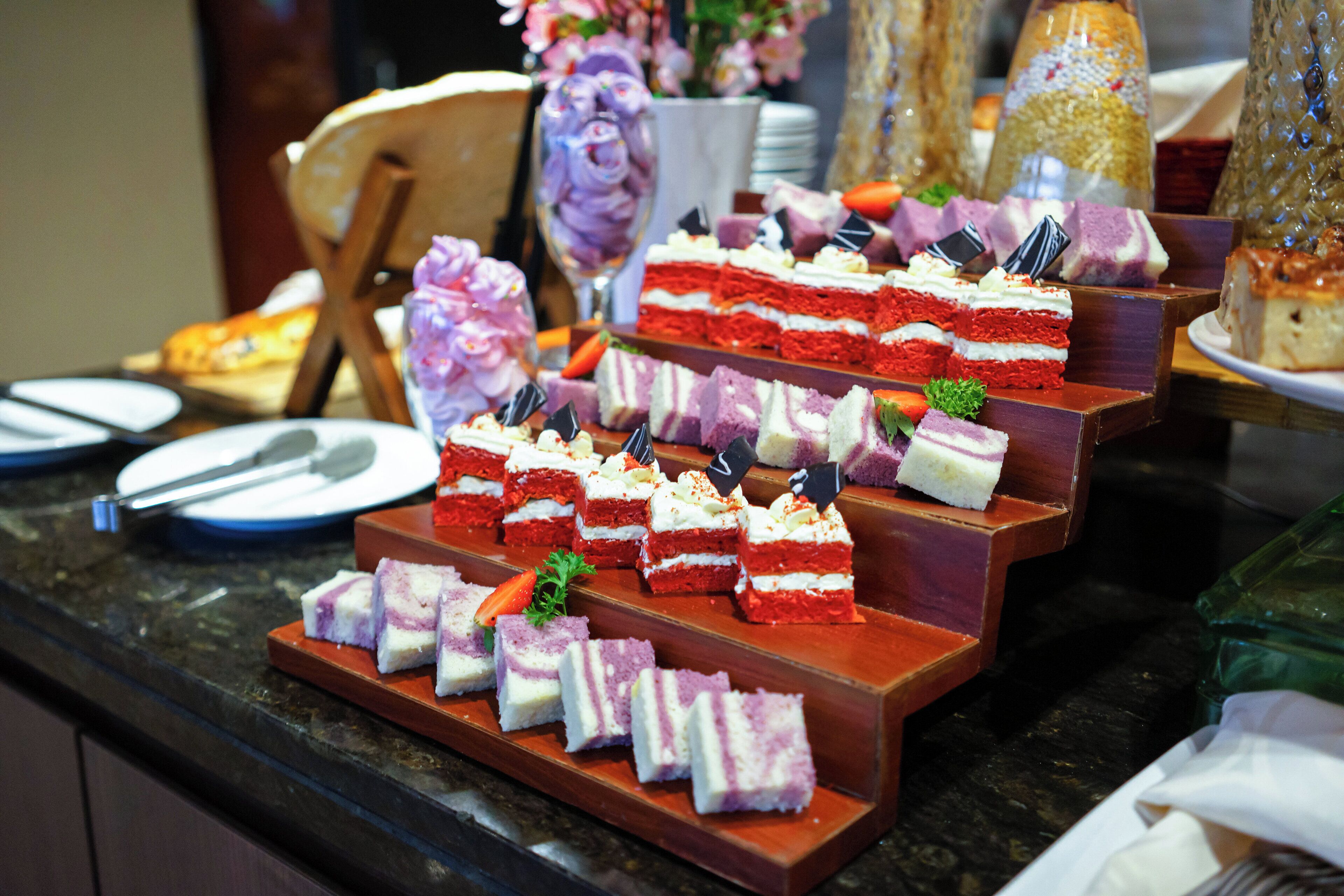 A buffet with tiered dessert displays including red velvet and purple layers.
