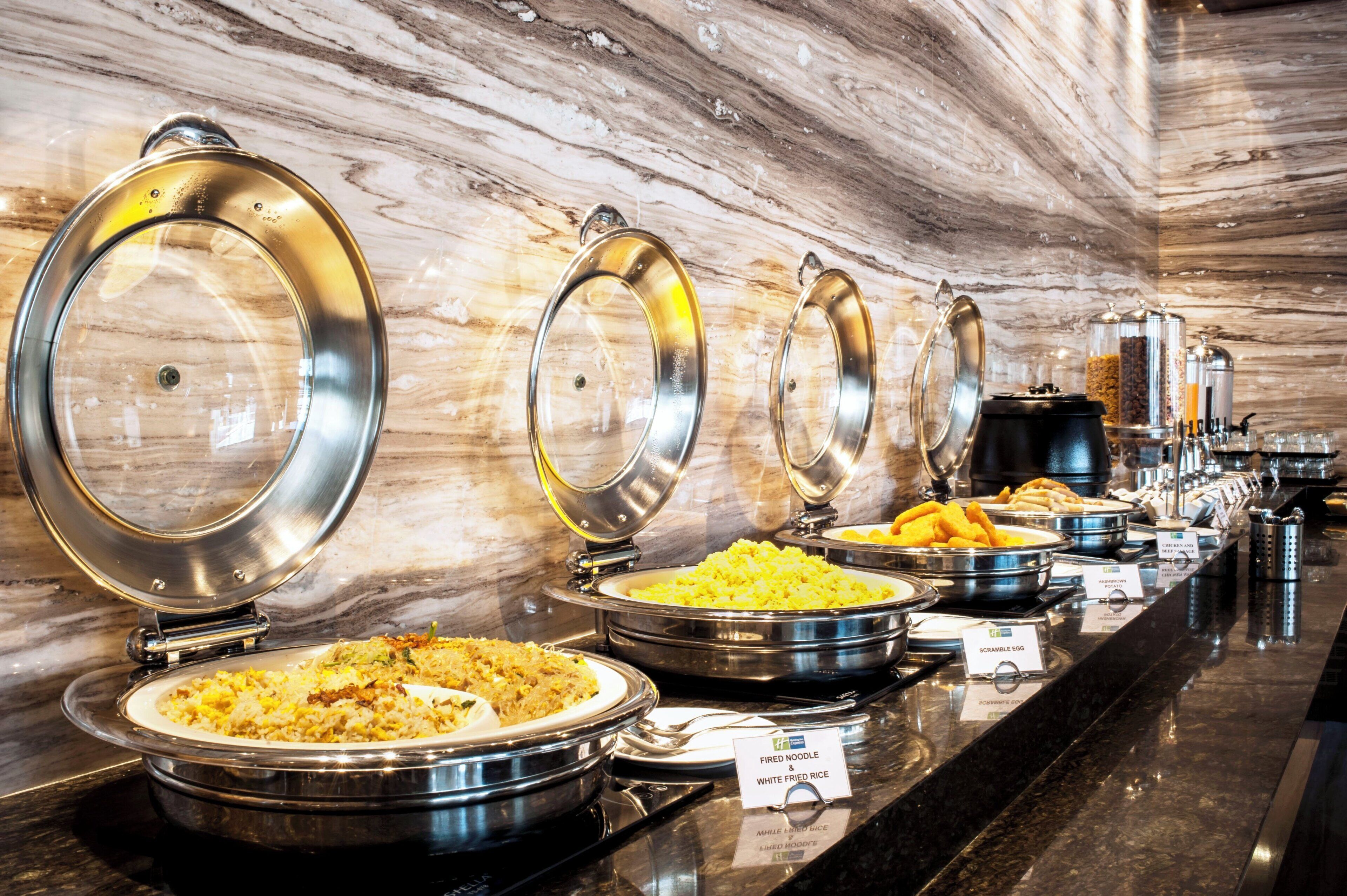 Un buffet proposant une variété de plats, notamment des œufs brouillés, du riz frit et des pommes de terre rissolées.