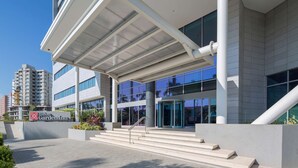 A modern hotel entrance with a glass facade, a covered walkway, and a visible Hilton Garden Inn sign. - Hilton Garden Inn Barranquilla (Barranquilla)