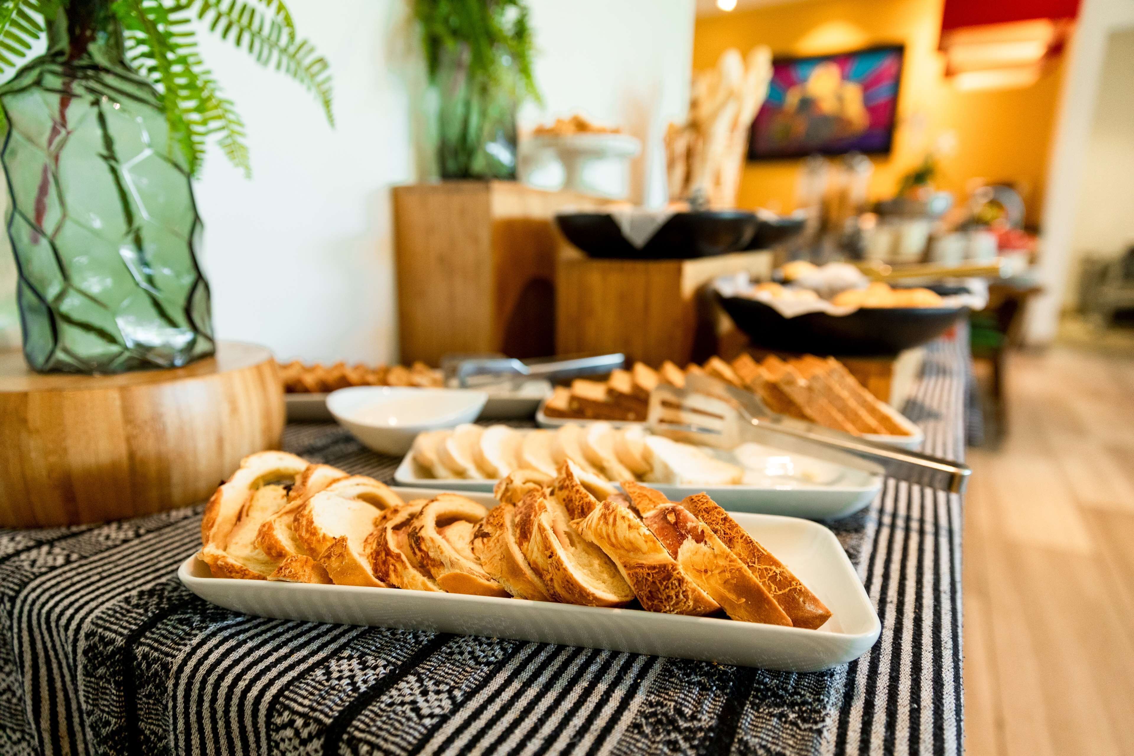 Una mesa de buffet con diversos alimentos, incluyendo pan y pasteles, en un espacio interior bien iluminado.
