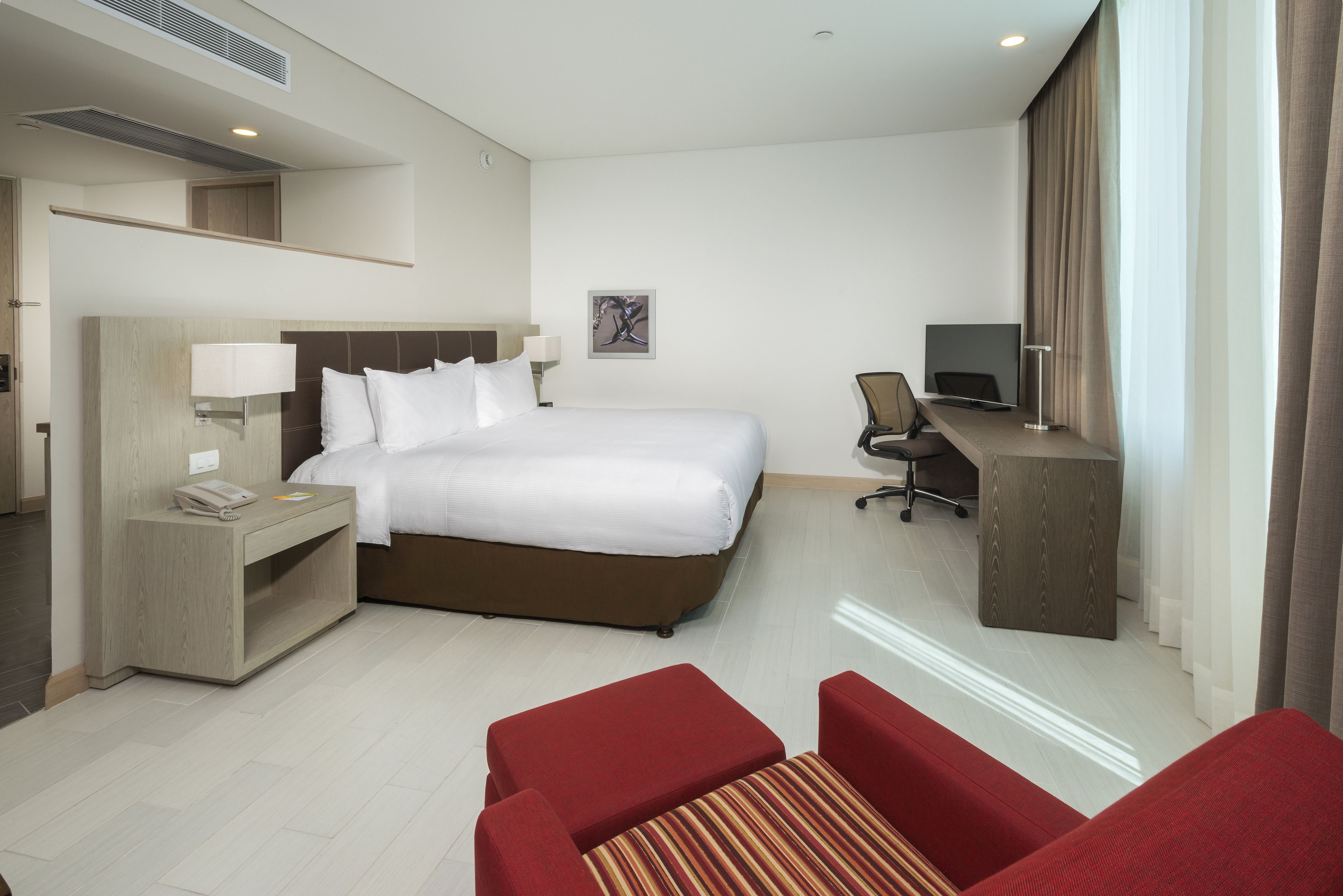 A hotel room with a bed, a desk, a chair, and a TV.