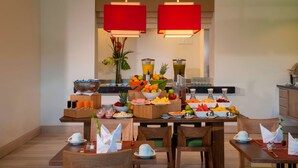 A breakfast buffet with various fruits, beverages, and a vase of flowers. - Hilton Garden Inn Barranquilla (Barranquilla)