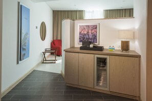 A modern hotel room with a wooden cabinet, a red chair, and a large window with curtains.