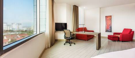 Una habitación de hotel moderna con un ventanal grande, un escritorio, un sofá rojo y una cama.