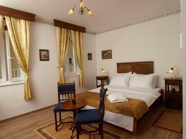 Habitación de hotel con cama, una silla, una mesa y un escritorio con lámparas.