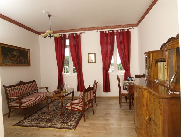 A traditional living room with a sofa, chairs, a table, and a wooden cabinet.