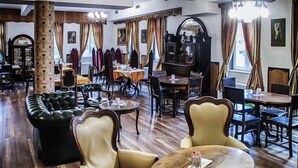 Un comedor amplio con piso de madera, asientos de cuero y una araña. Mesas dispuestas para comer, con sillas.