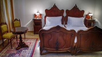 A traditional bedroom with a double bed, two bedside tables, a small round table, and a chair.