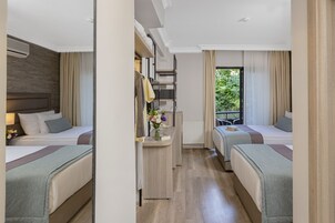 Habitación de hotel con dos camas, un escritorio pequeño con un florero y vistas a zonas verdes.
