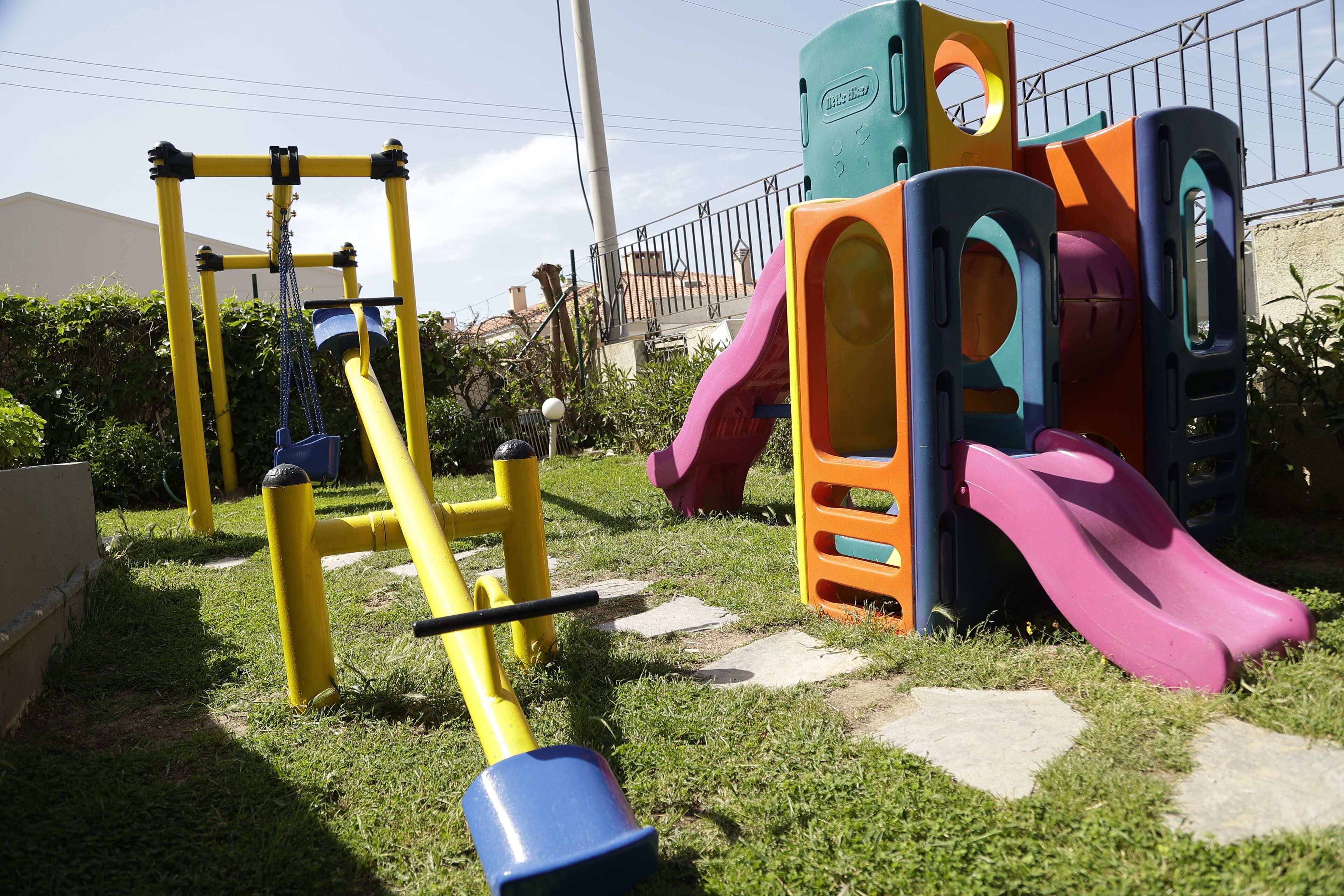 Un parque infantil con estructuras de juego amarillas y naranjas, incluyendo un tobogán y una estructura para escalar.