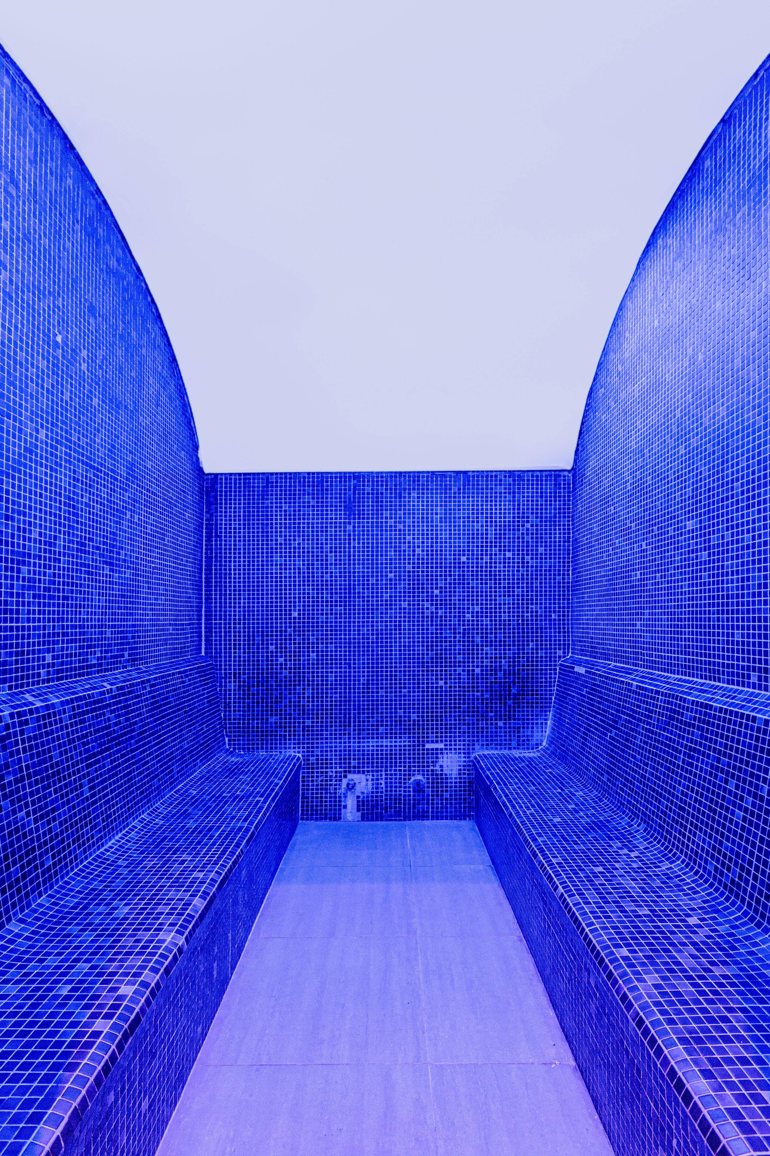 A blue-tiled room with a bench and a sink.