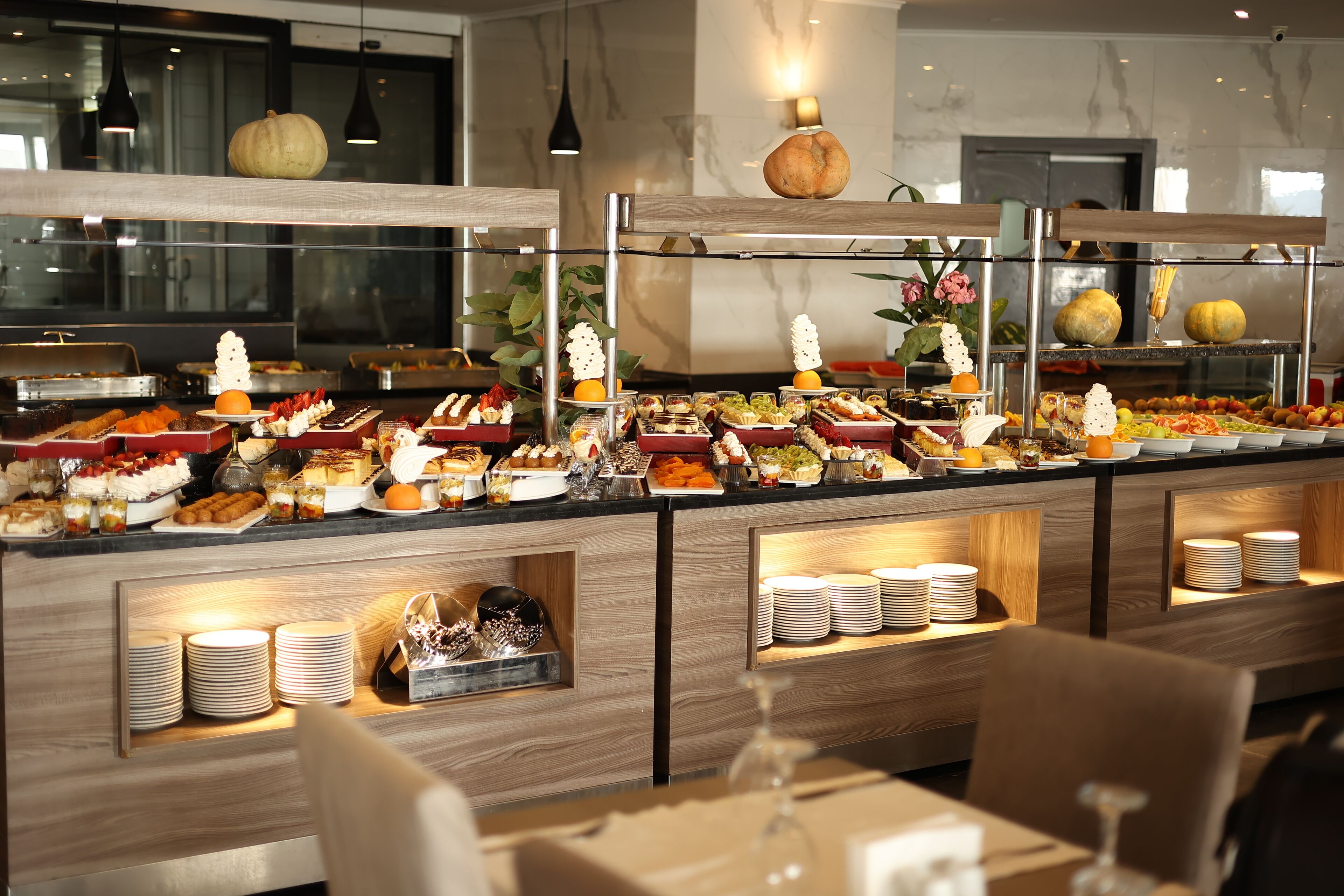 A buffet with various food items and a variety of plates and bowls.