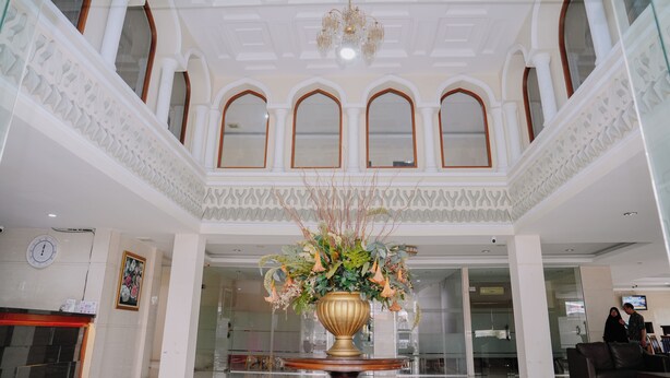 Un hall d’entrée agrémenté d’un grand vase décoratif, de fenêtres en arc de cercle et d’un lustre.