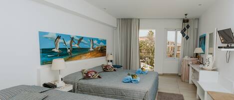 Habitación de hotel con dos camas, un cuadro de gaviotas, un escritorio y vistas al exterior.