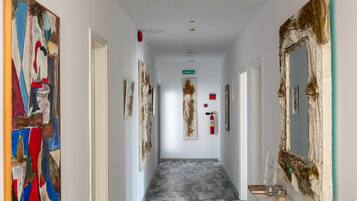 Un corridoio con pavimento decorato, una panca e opere d'arte alle pareti.