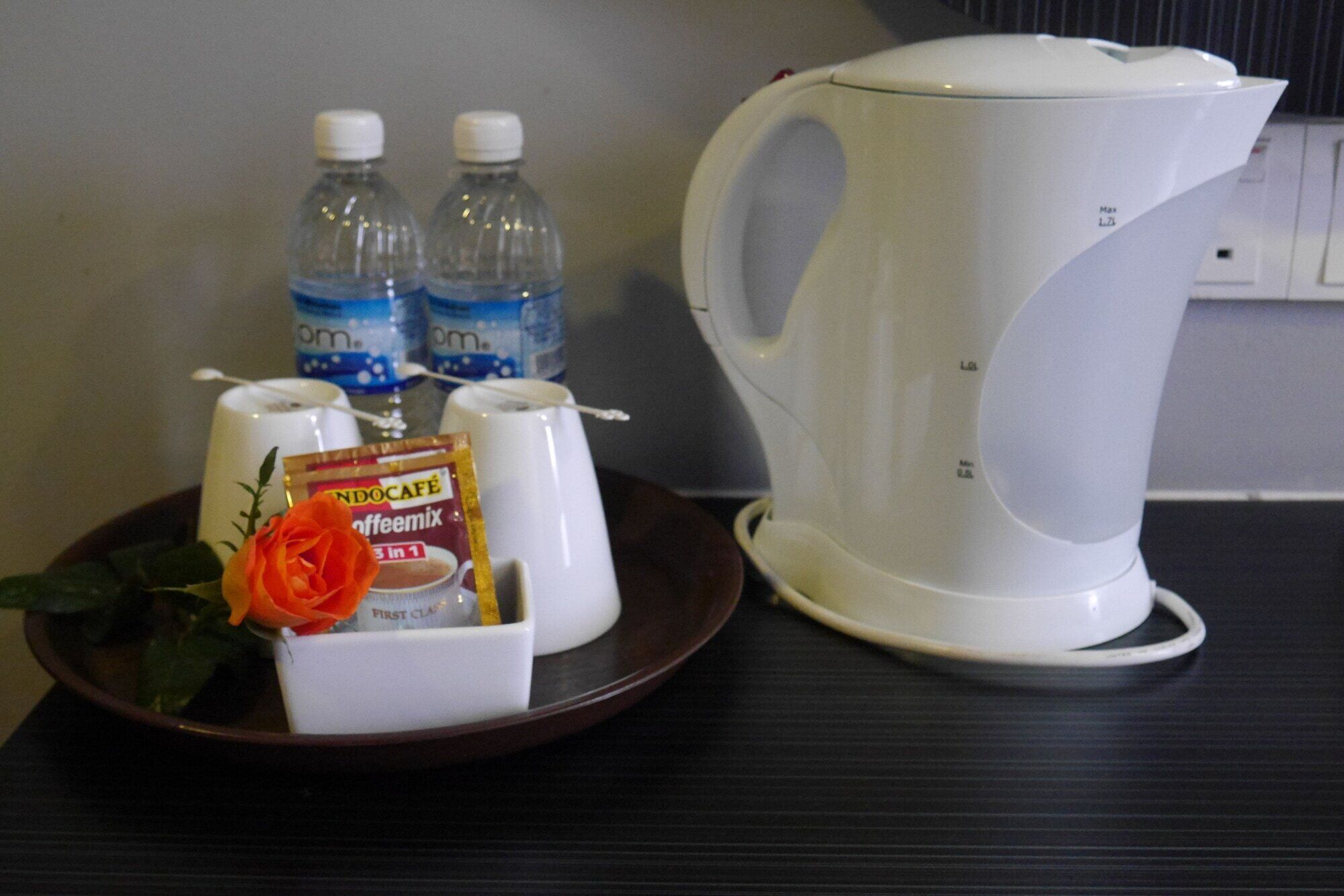 A tray with a coffee maker, bottled water, and a coffee creamer packet.