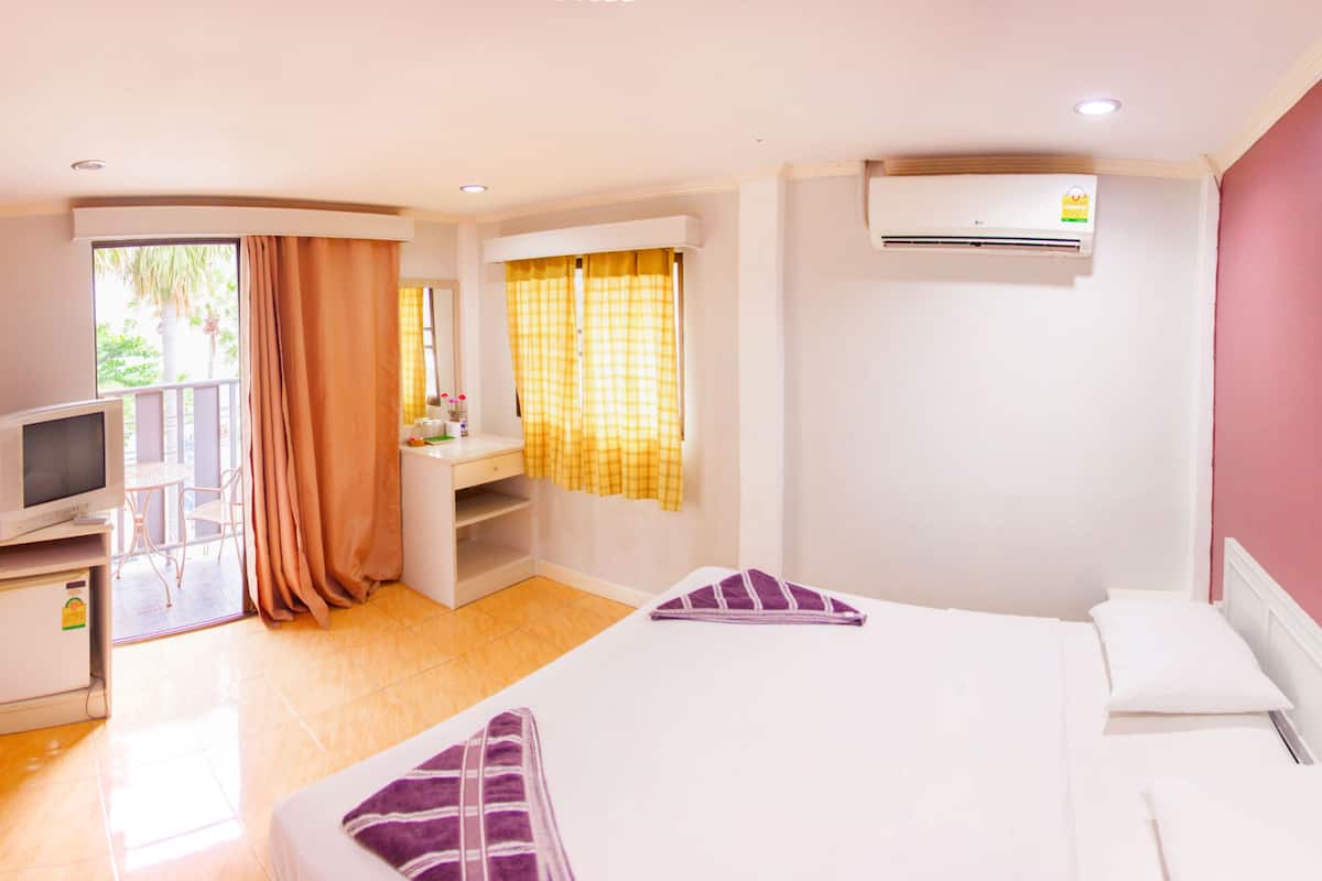 Habitación de hotel con cama, escritorio con computadora, televisor y ventana con cortinas.