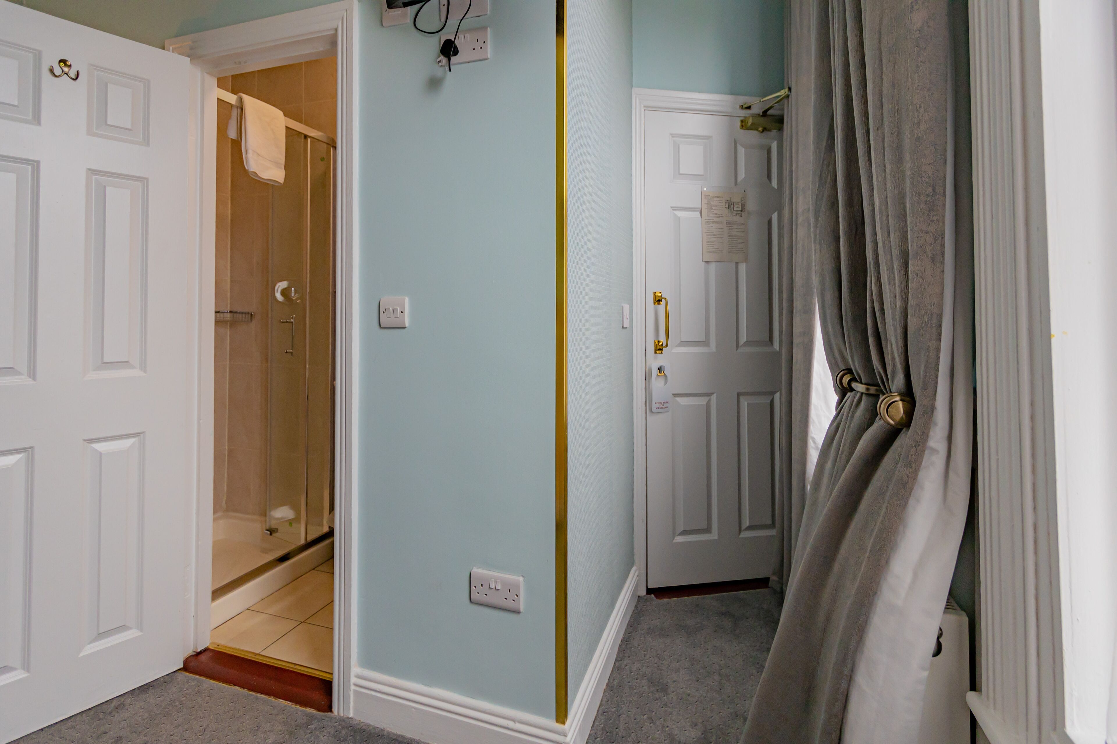 A hallway with a shower, a door with a note, and a curtain.