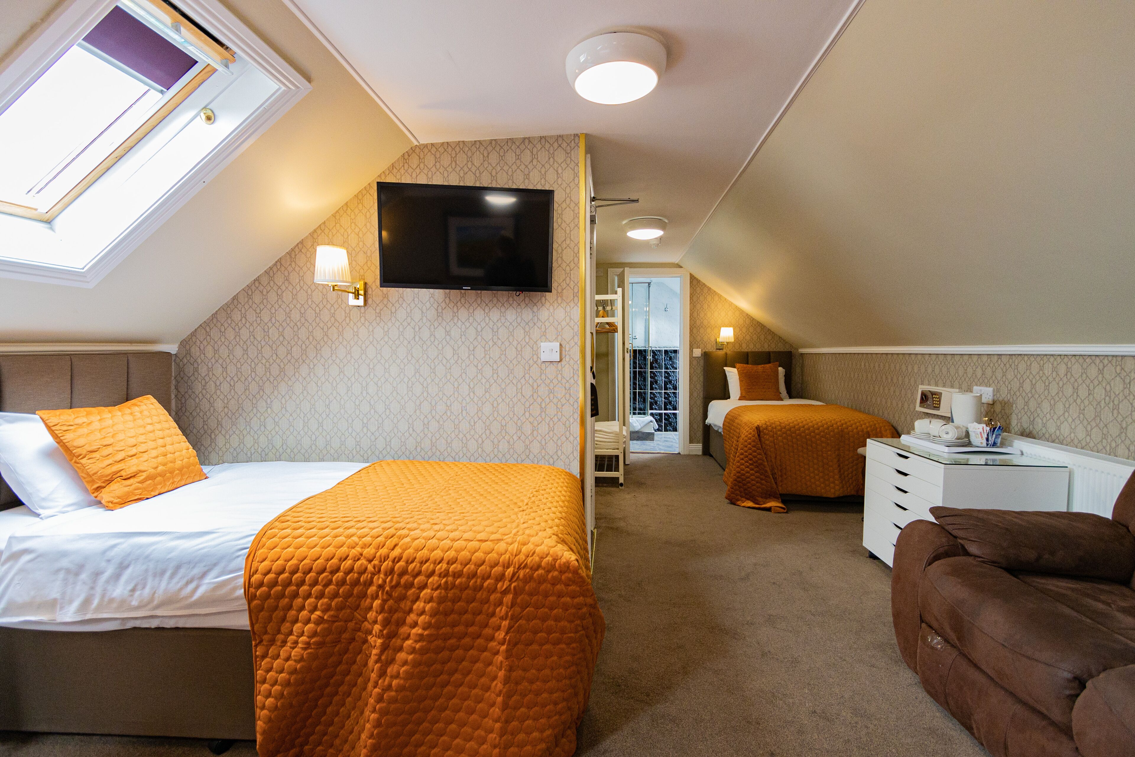 A bedroom with a bed, a sofa, a TV, and a desk.