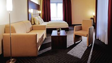 Una habitación de hotel con cama, sofá, sillón y mesa de centro.
