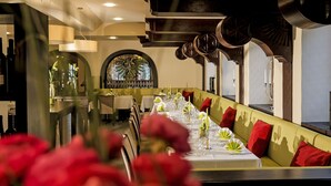 Una larga mesa de comedor vestida con manteles blancos, velas y servilletas verdes.