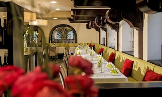 Una larga mesa de comedor vestida con manteles blancos, velas y servilletas verdes.