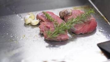 Raw steak with herbs and garlic on a cooking surface.