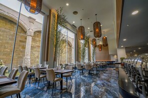 A spacious restaurant with marble flooring, multiple dining tables, and hanging pendant lights. - Harmoni One Convention Hotel & Service Apartments (Batam)