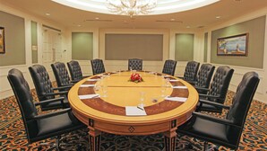 A conference room with a round table, black leather chairs, a chandelier, and a patterned carpet. - Harmoni One Convention Hotel & Service Apartments (Batam)