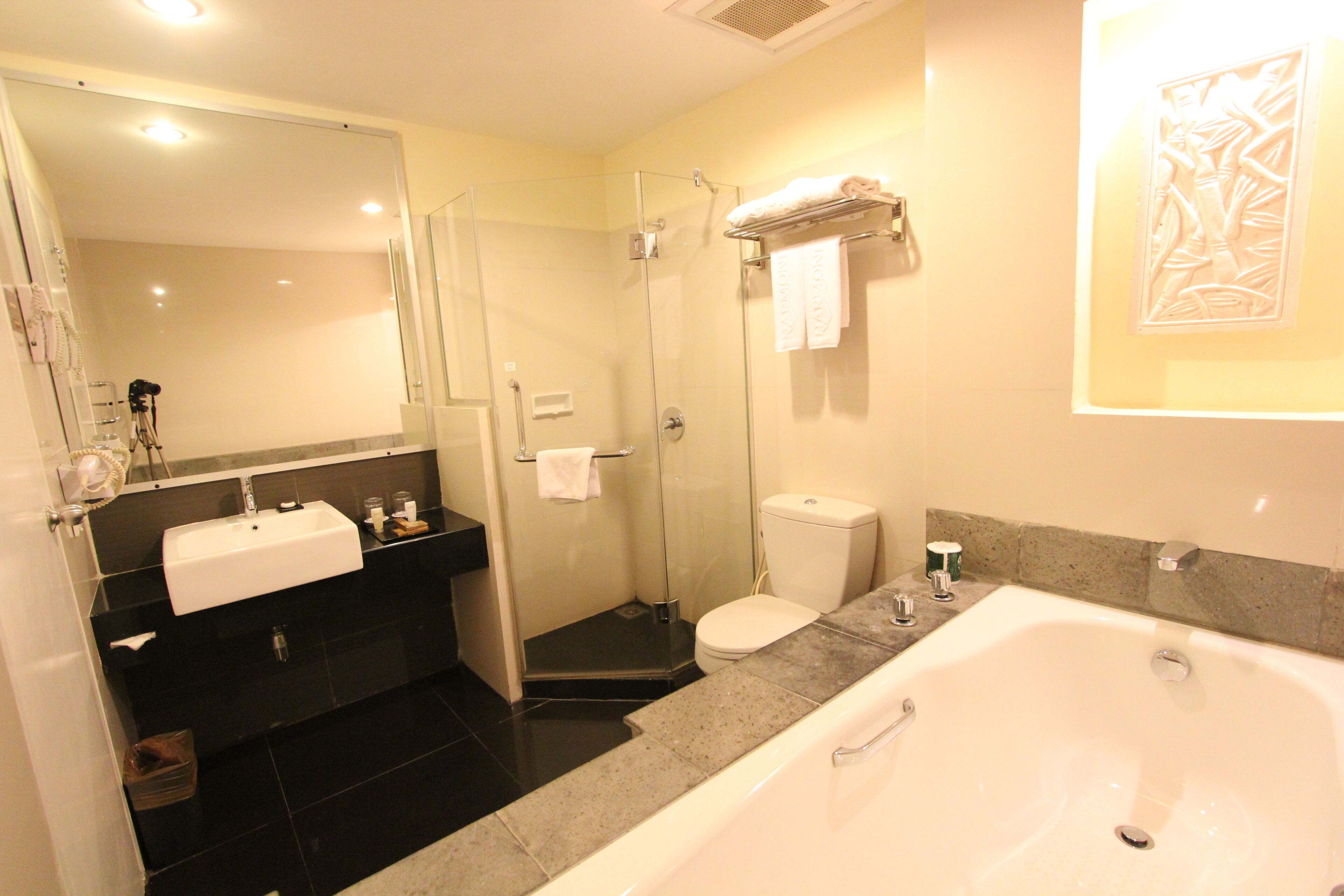 A modern bathroom with a glass-enclosed shower, a white sink, a bathtub, and a toilet.