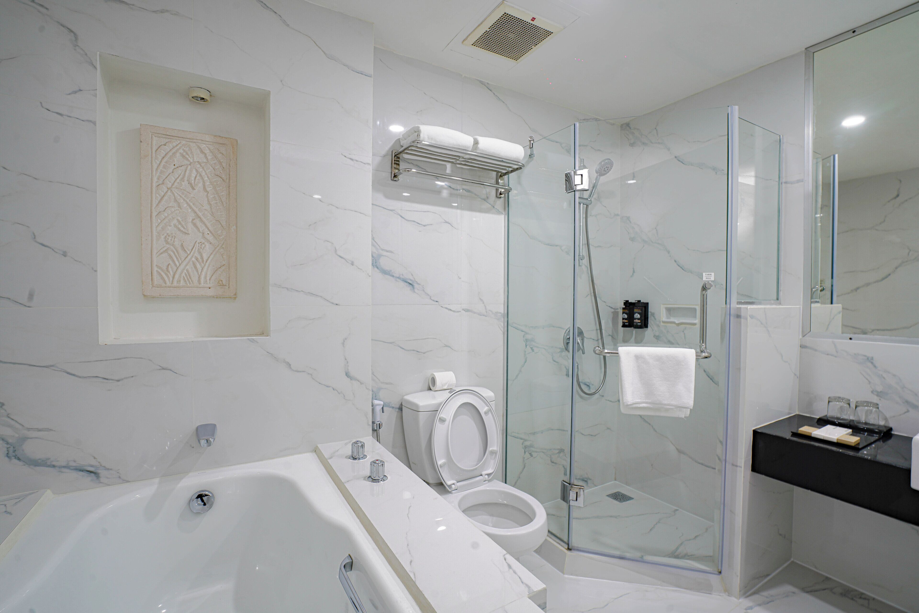 A modern bathroom with a glass-enclosed shower, a bathtub, and a toilet.