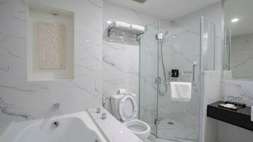 A modern bathroom with a glass-enclosed shower, a bathtub, and a toilet.