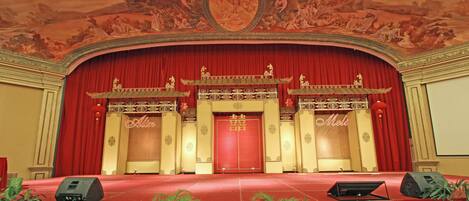 Un escenario con cortinas rojas, alfombra roja y decoraciones chinas tradicionales.